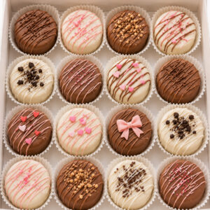 Assorted chocolate covered Oreos decorated with white chocolate, milk chocolate, pink drizzle, sprinkles, hearts, bows, and cookie crumbs