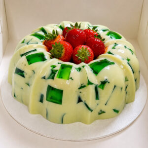 Gelatina de mosaico with green jelly pieces and fresh strawberries in the center