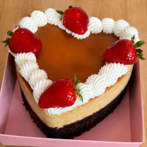 Heart-shaped small chocoflan with caramel flan, chocolate cake, whipped cream, and strawberries