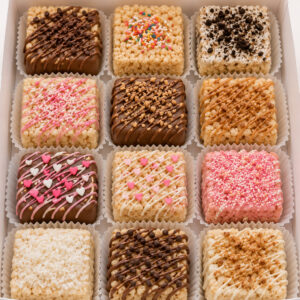 Assorted Rice Krispy treats decorated with chocolate drizzle, caramel, sprinkles, cookie crumbs, hearts, and pink icing